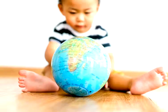 What Makes a Good Parent? Is Acting on Climate Change as Important as Love and Bedtime Stories? a child sitting on the floor playing with a world globe